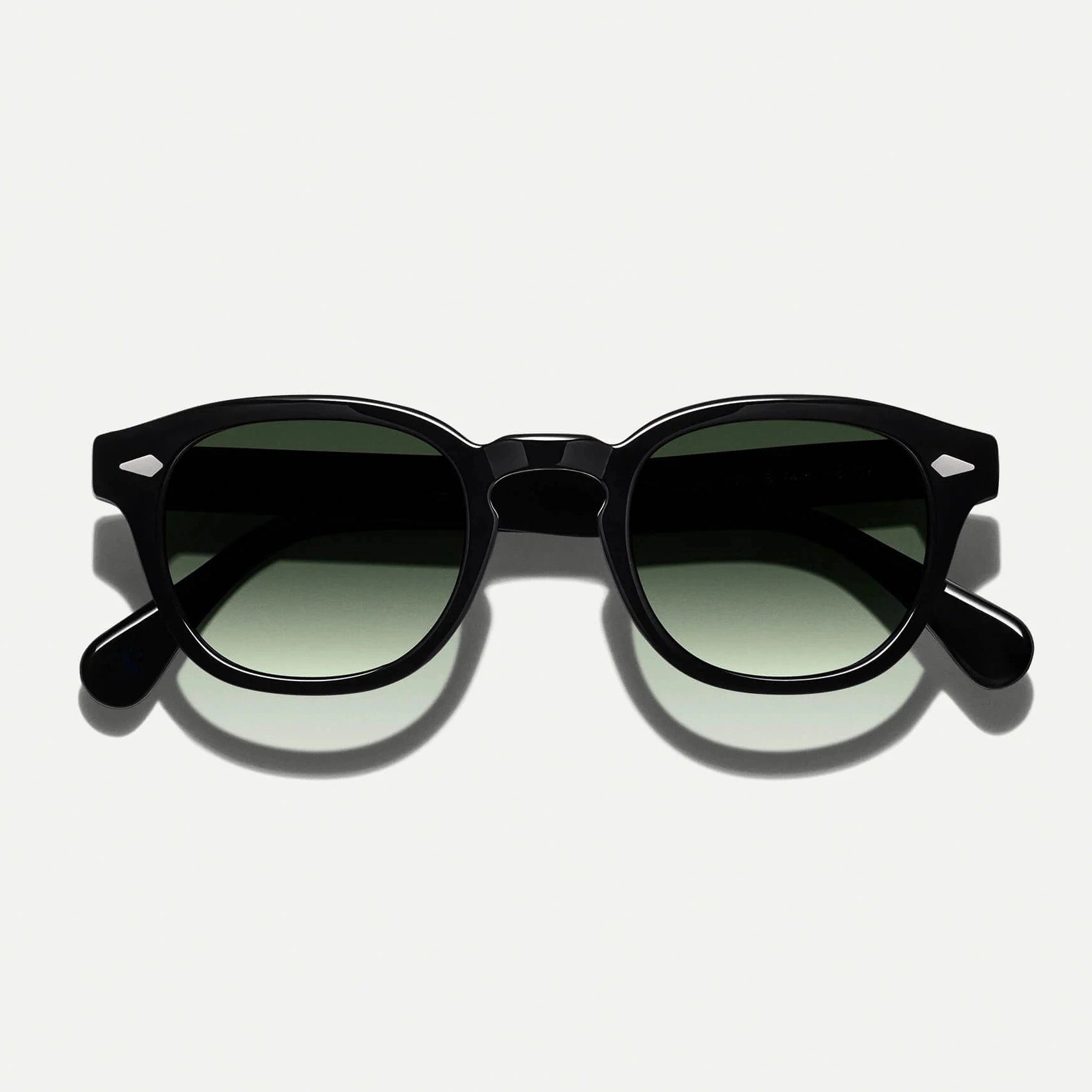 A pair of sunglasses with black frames and green tinted lenses.